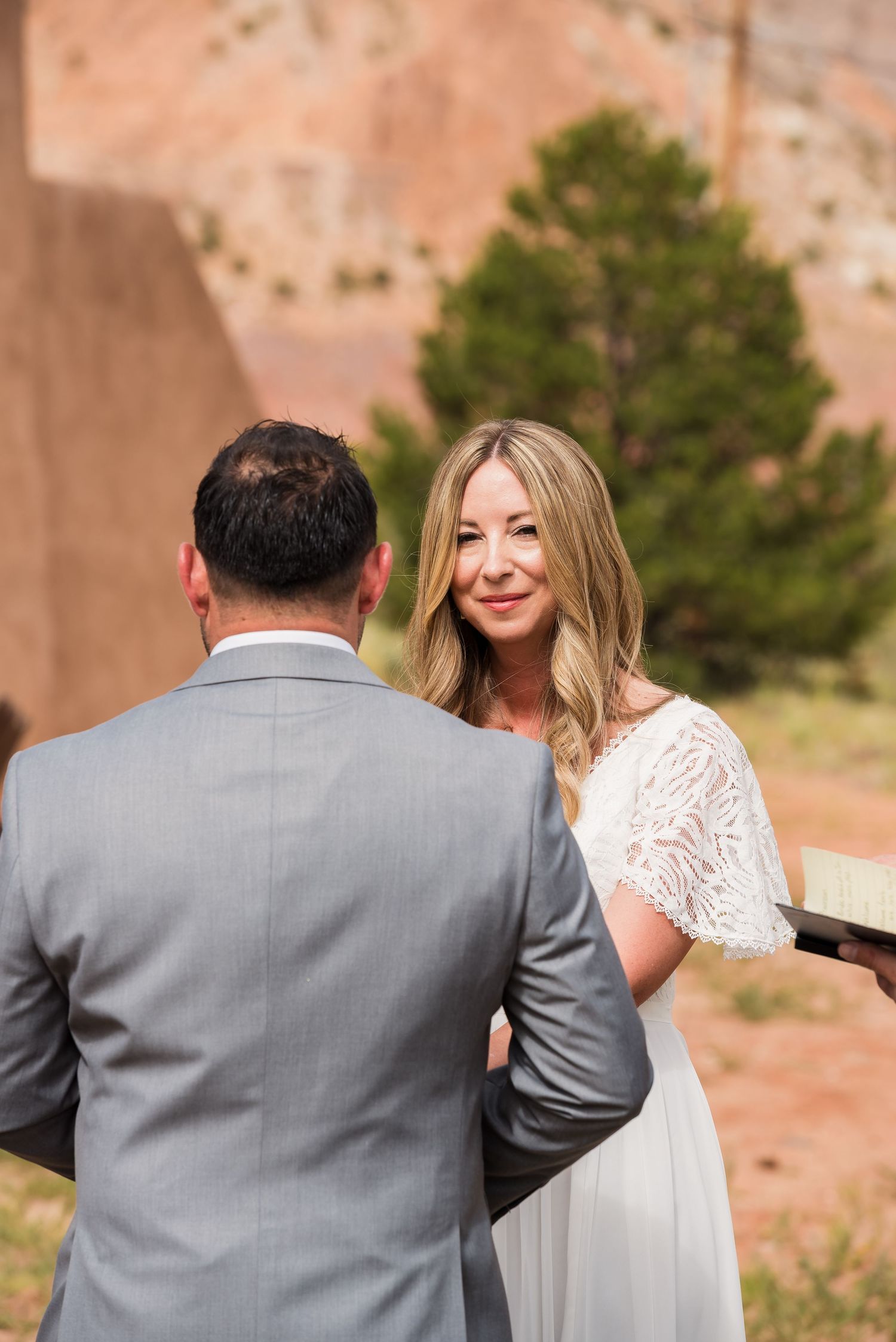 A couple exchanges vows during an intimate outdoor ceremony against red rock formations.