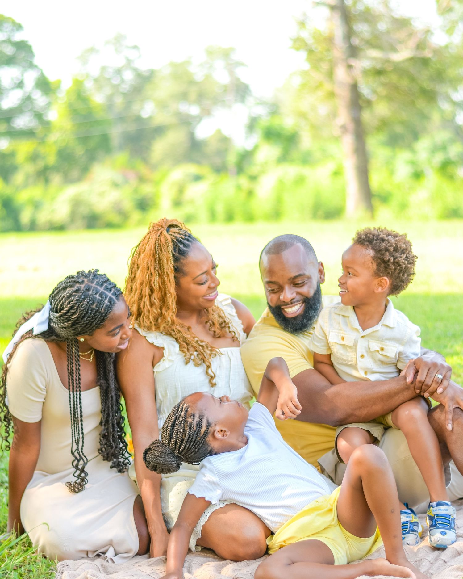 Group enjoying playful moments together while relaxing on grass in a sunny park.