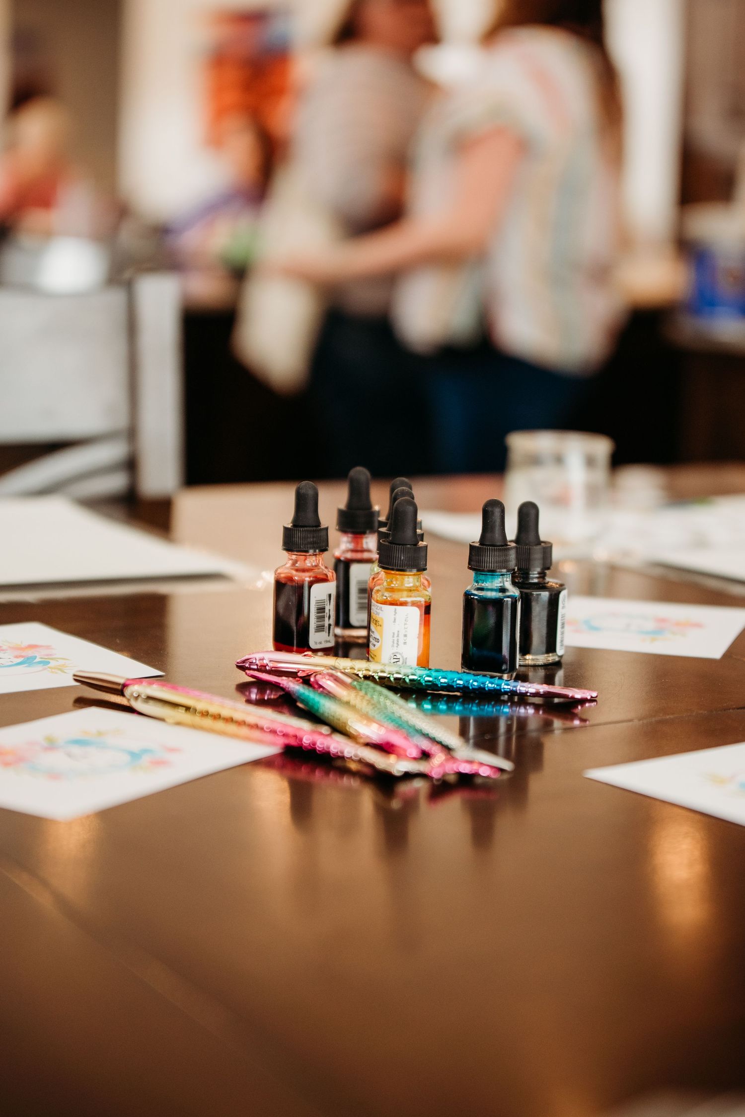 Essential oils, dropper bottles and art supplies arranged on wooden table surface.