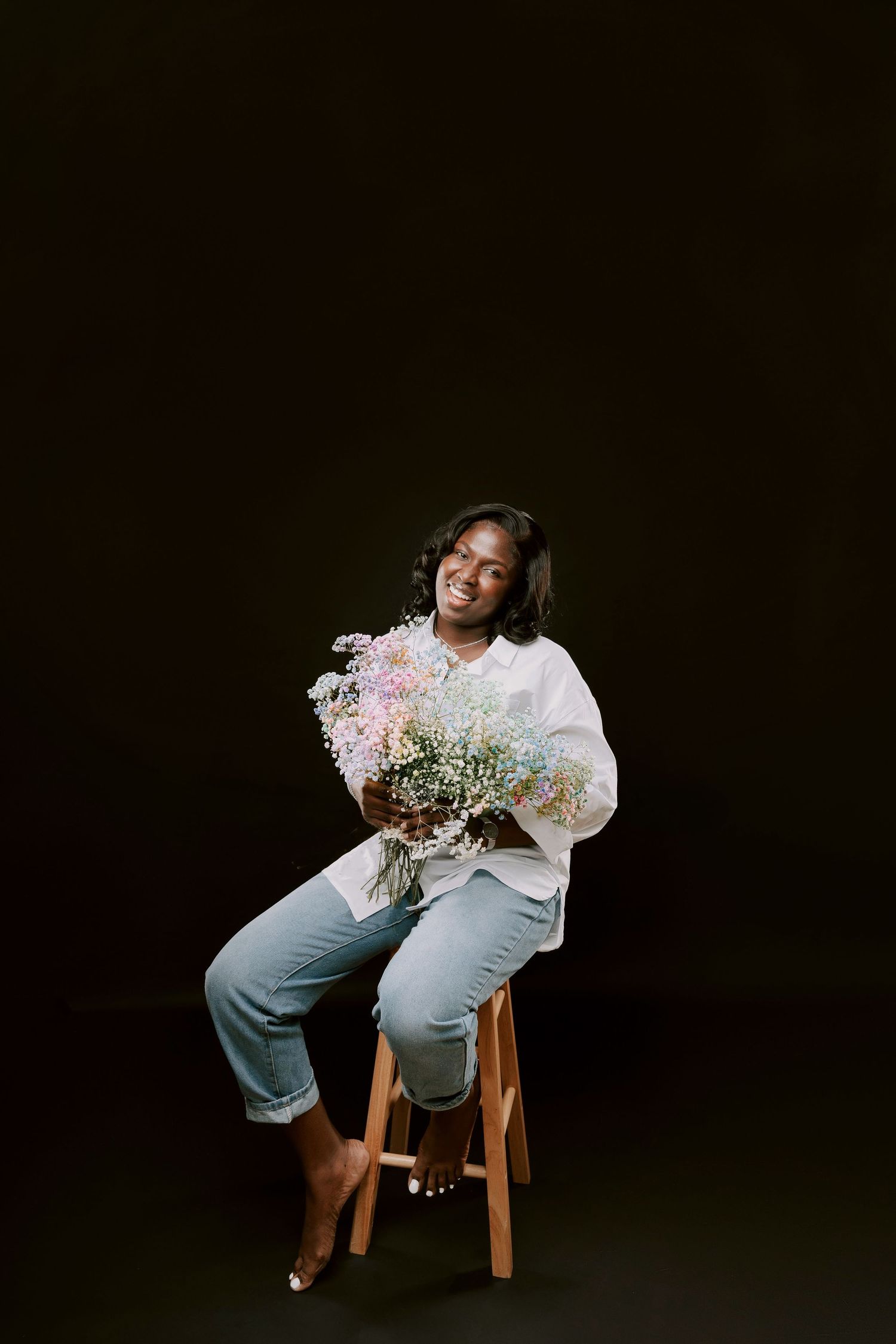 Glamour studio photo of a beautiful black woman wearing a casual fit on her 40th Birthday holding colourful flowers