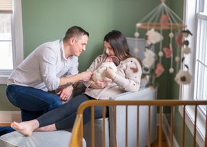 In home newborn session of a mother and father and their sweet newborn sitting in the nursery holding their baby. Wrightstown NJ