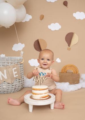 Cake smash session for first birthday with a hot air balloon theme. Smiling about to break into cake. Wrightstown NJ Family Photographer