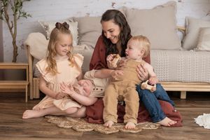 Studio session with mother and 3 young children snuggled up close sitting on the floor in a candid moment. Wrightstown NJ