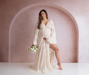 Maternity shot of a women in a lace white dress holding a bouquet of flowers with a arch backdrop. Wrightstown NJ Maternity Photographer