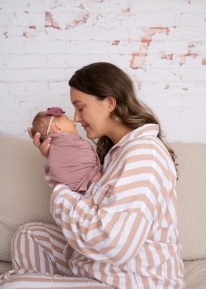 Mother in stripe pajamas holding her swaddled newborn up close to her face. Wrightstown NJ Maternity Newborn Photographer