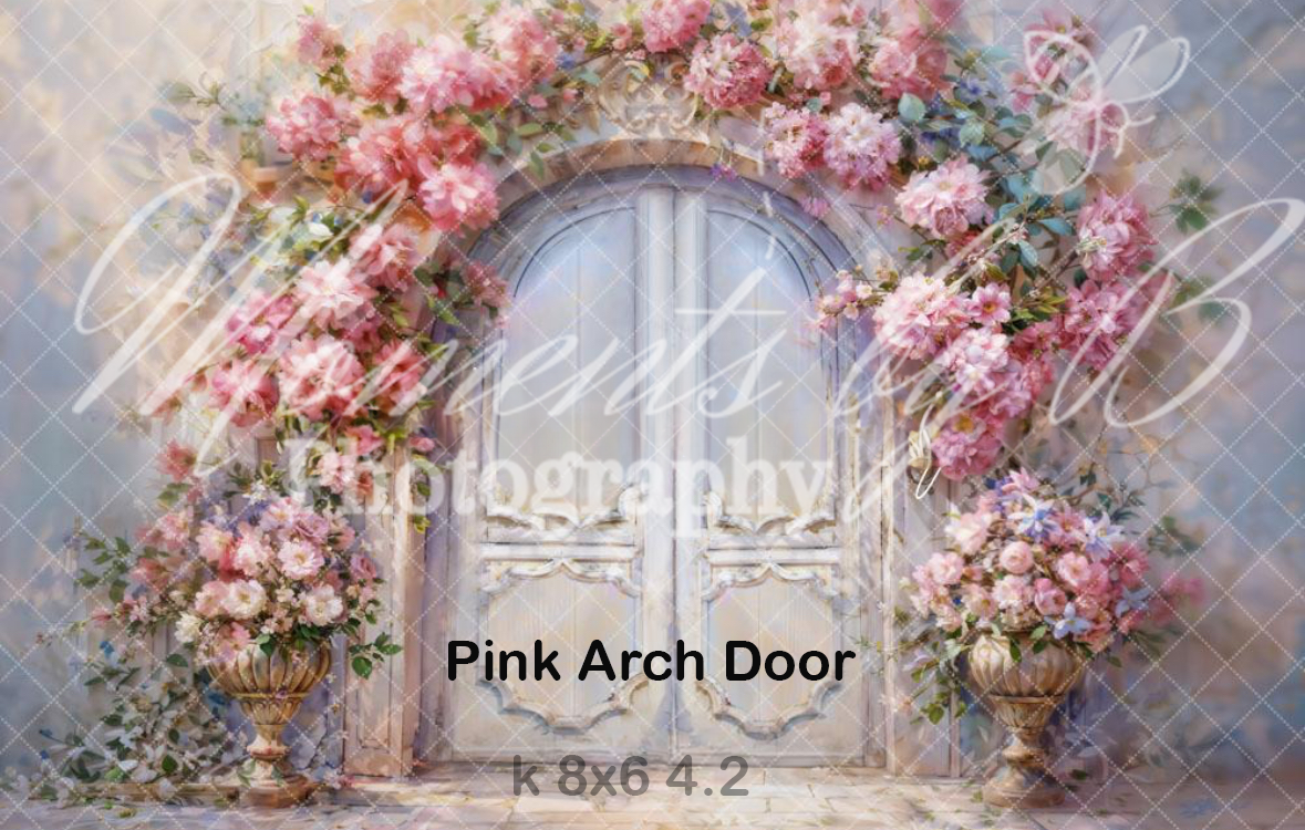 Romantic pink floral arch with climbing roses framing a vintage door in a dreamy garden setting.