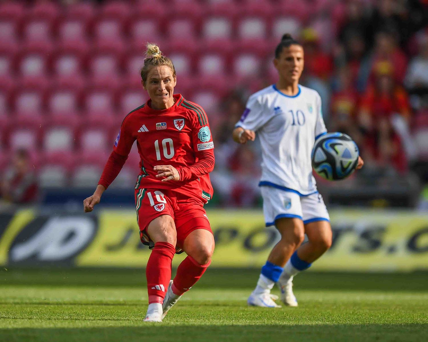 Soccer player in red uniform controls ball during competitive match.