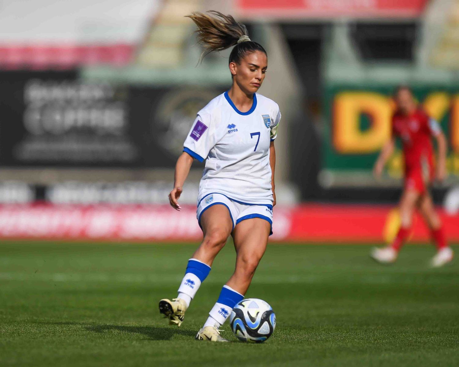 Soccer player in white uniform prepares to kick ball during match.