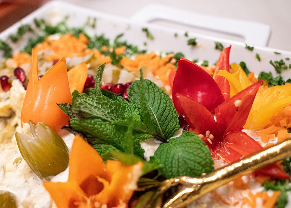 Elegant food platter garnished with carved vegetables, mint leaves, and colorful fresh produce.