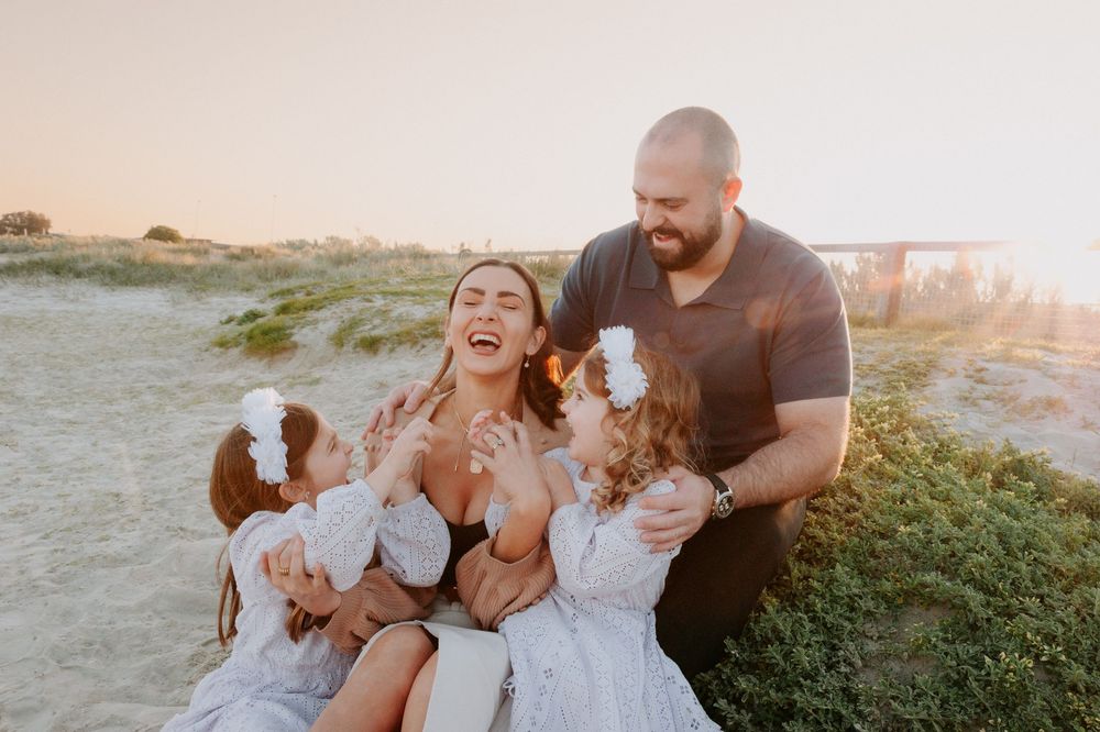 A joyful family embraces and laughs together on a grassy hill during golden hour at sunset.
Altona Family Photographer Melbourne