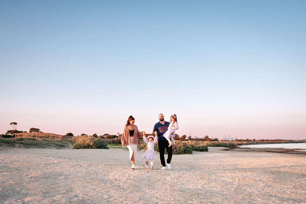 At sunset, figures embrace and play on a sandy beach with soft golden light.
Altona Family Photographer Melbourne