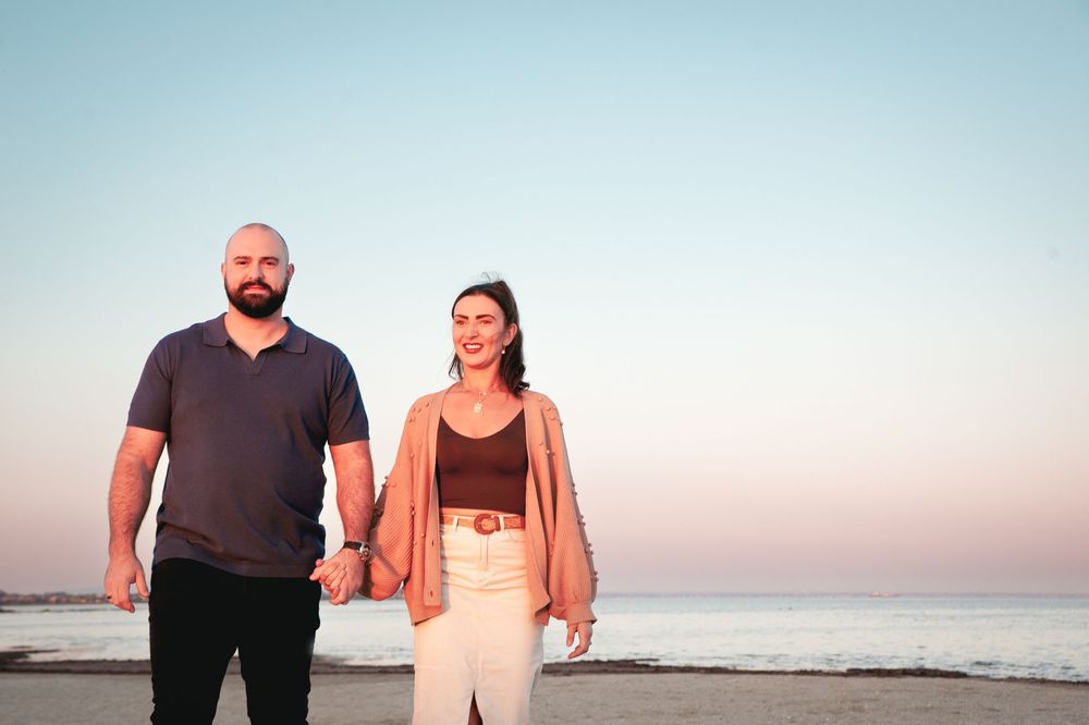 Couple in casual attire poses together at sunset on a beach with ocean waves in background.
Altona Family Photographer Melbourne