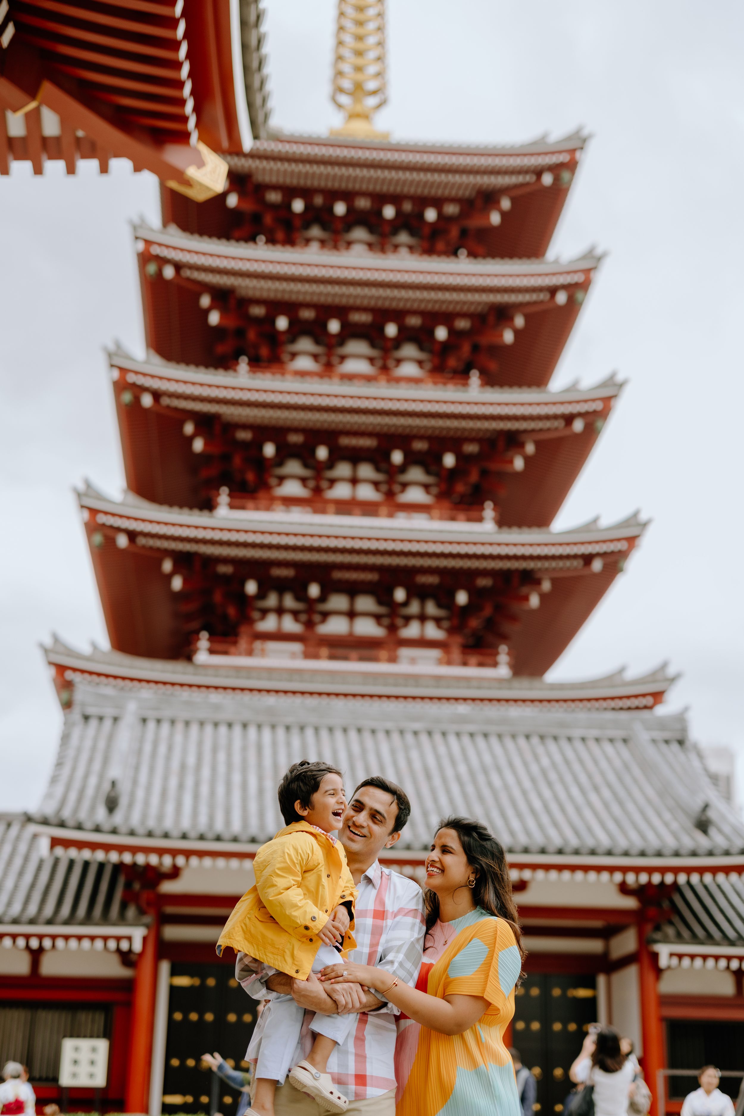 Family stands together in front of traditional red pagoda at Sensoji Temple in Tokyo.