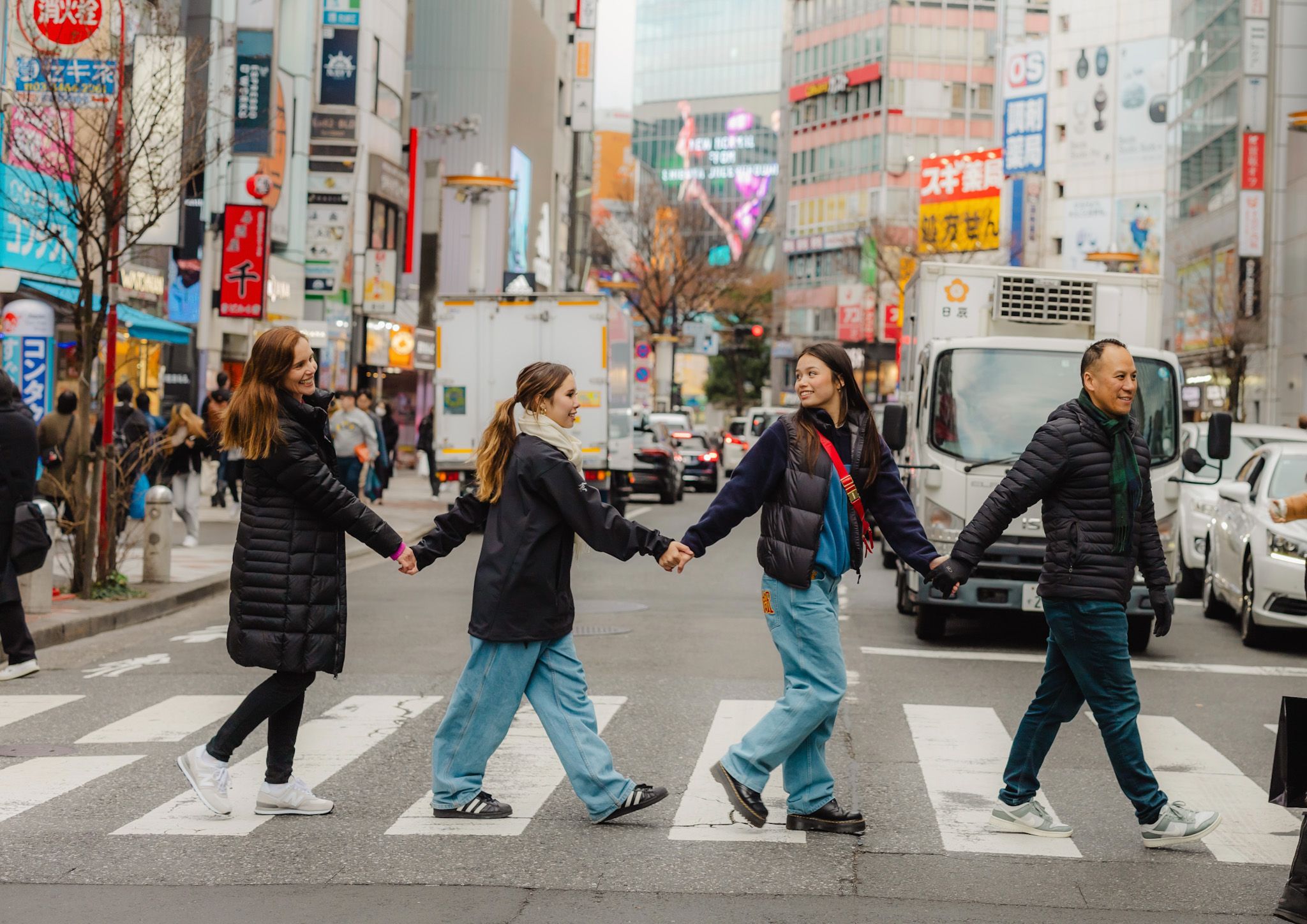 Group of friends crossing a busy street in Tokyo's vibrant shopping district.