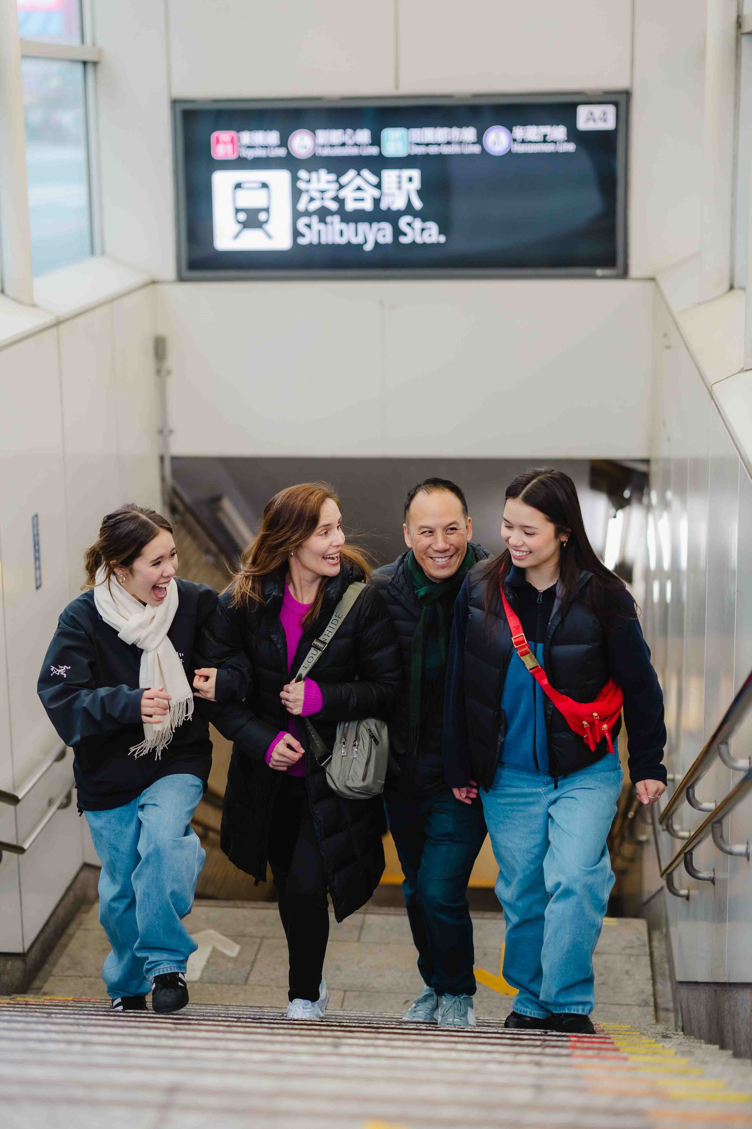 Group walking up stairs at Shibuya Station in Tokyo engaging in conversation.