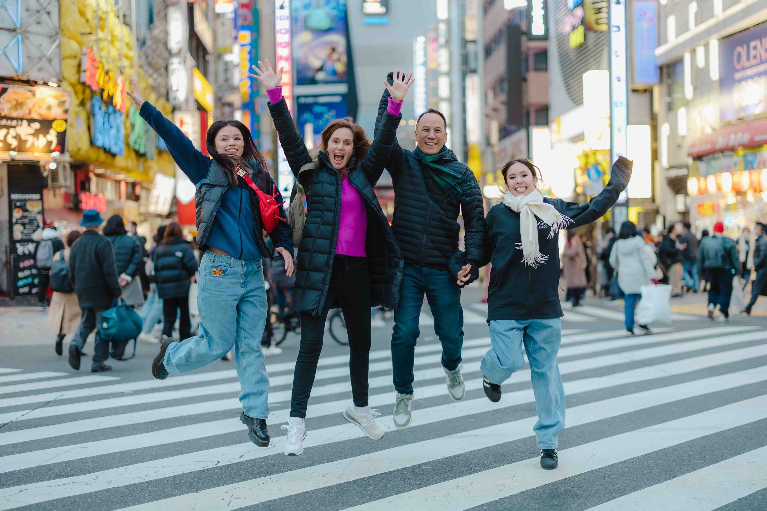 Group of friends jumping on a busy crosswalk in an urban city setting.