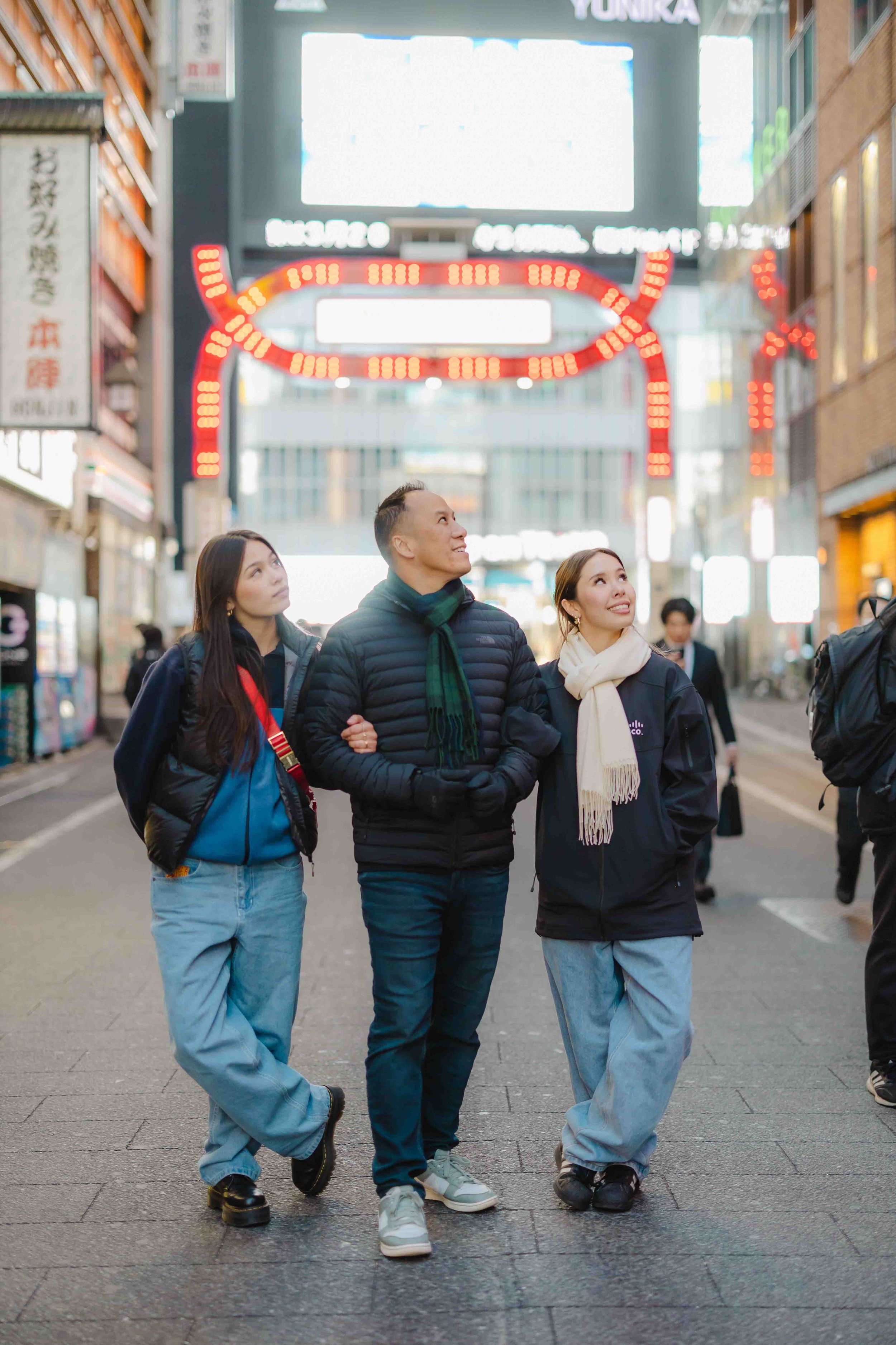 Group walking through illuminated streets of Tokyo at night under traditional red lanterns.