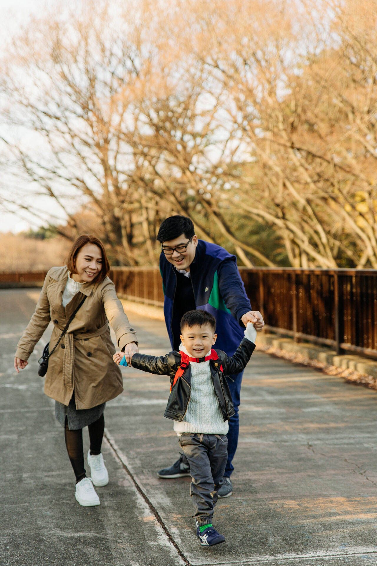 Family enjoying a playful moment walking on a pathway during fall season.