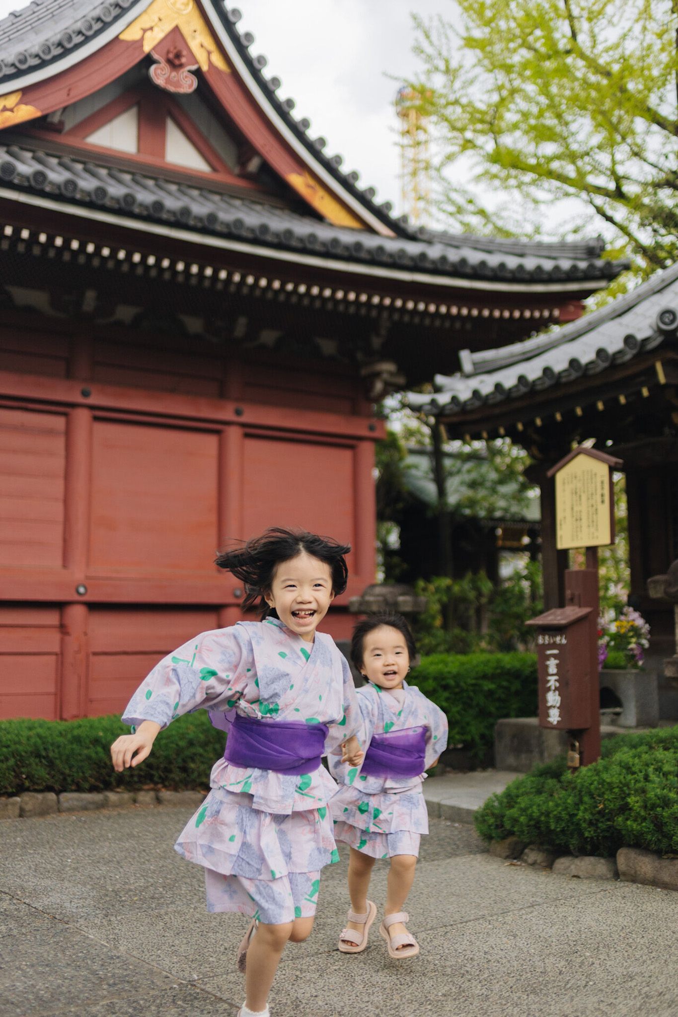 Children in colorful kimonos running joyfully outside traditional Japanese temple buildings.