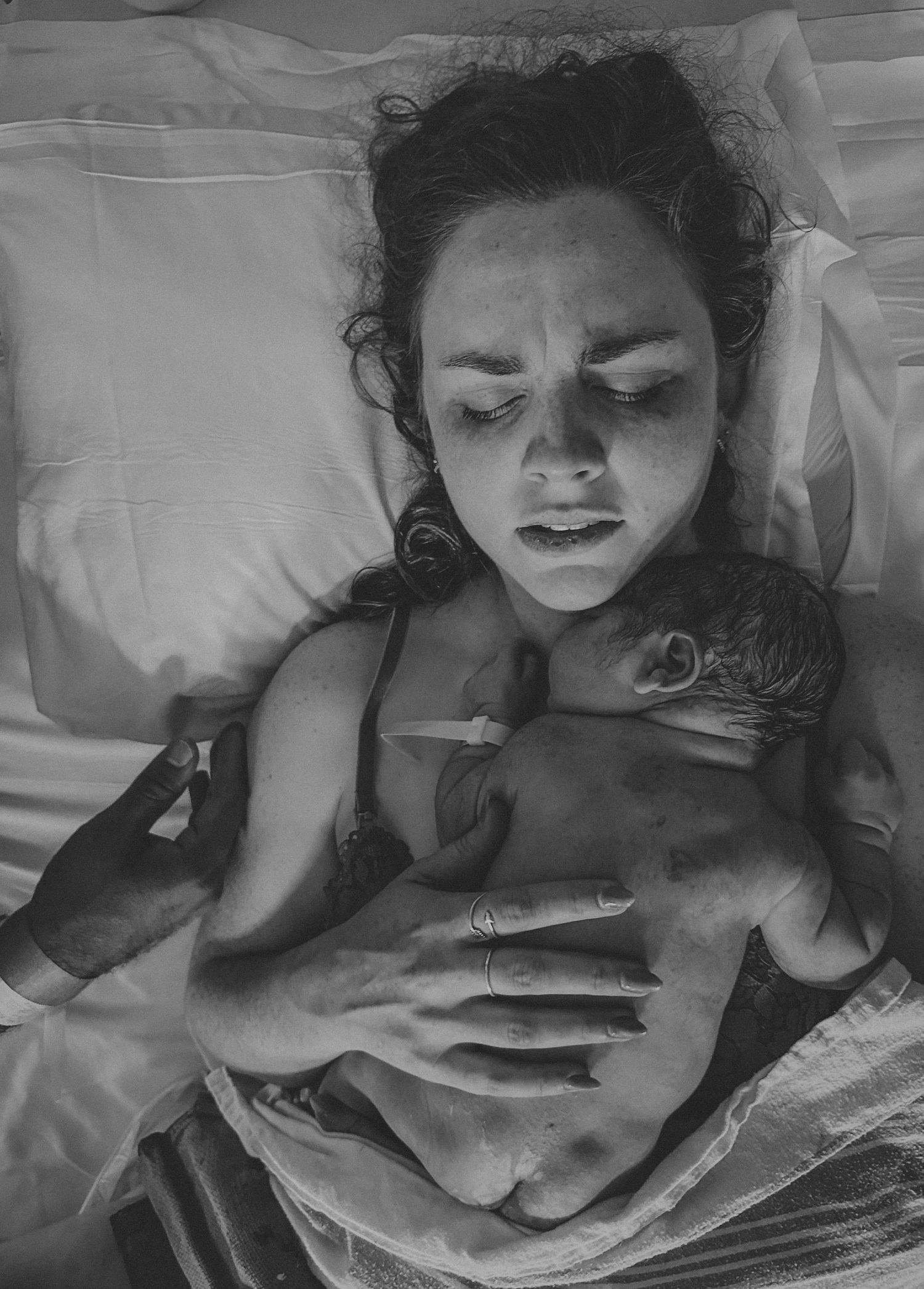 Black and white portrait of person resting on pillow with dramatic lighting.