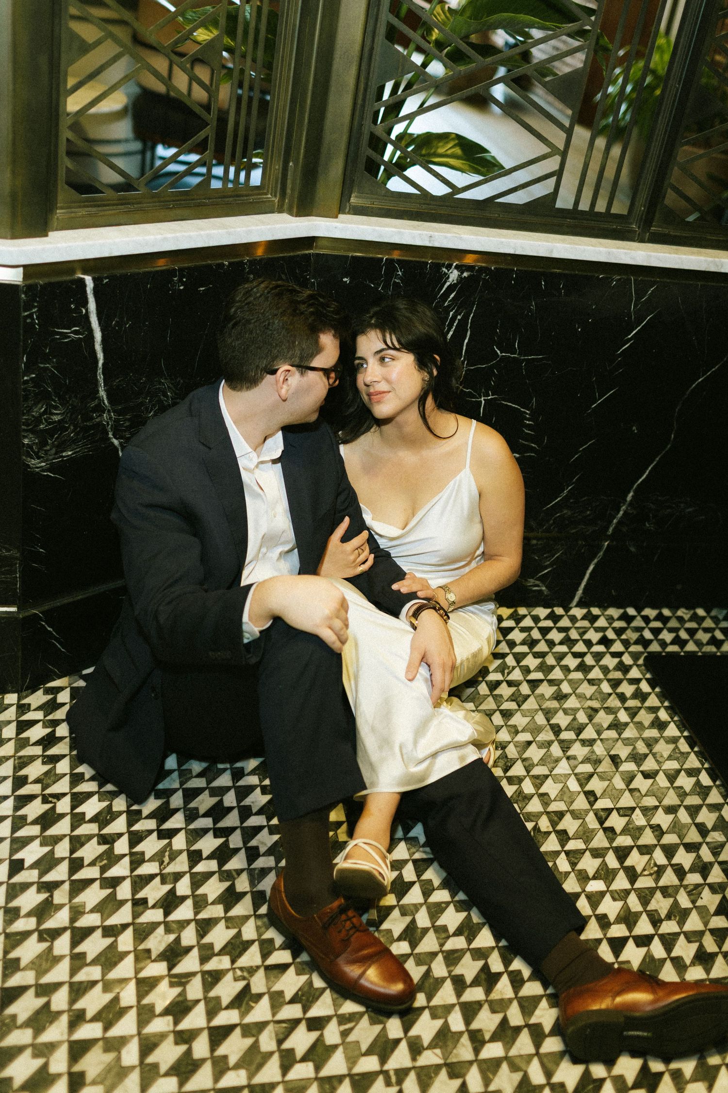 A couple sitting in a bar booth, the woman leans onto the shoulder of the man