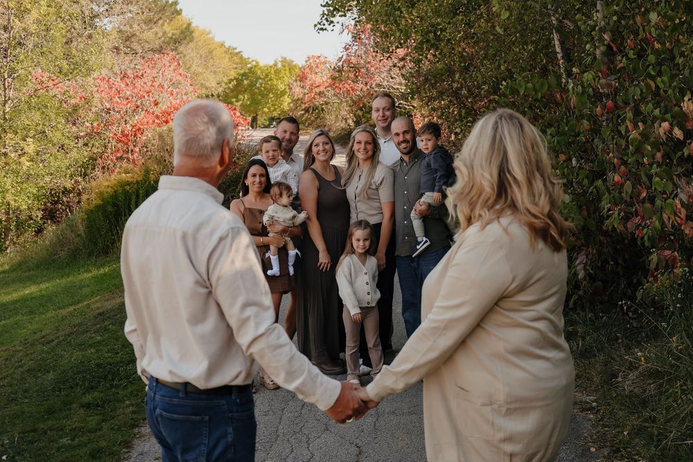 Wedding guests gather under autumn trees with vibrant red foliage during an outdoor celebration.