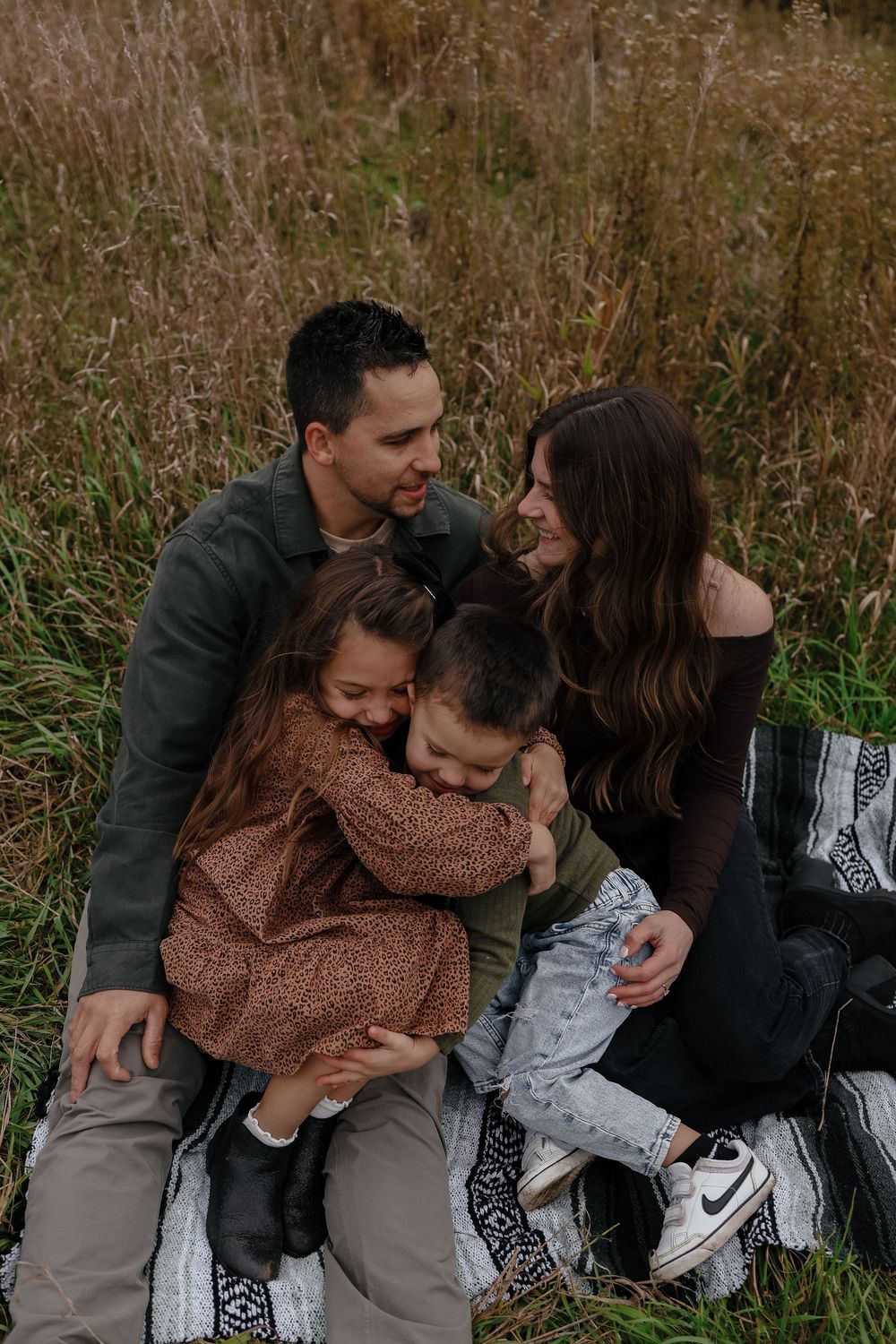 Family sharing playful candid moments together in a field of tall grass during autumn.
