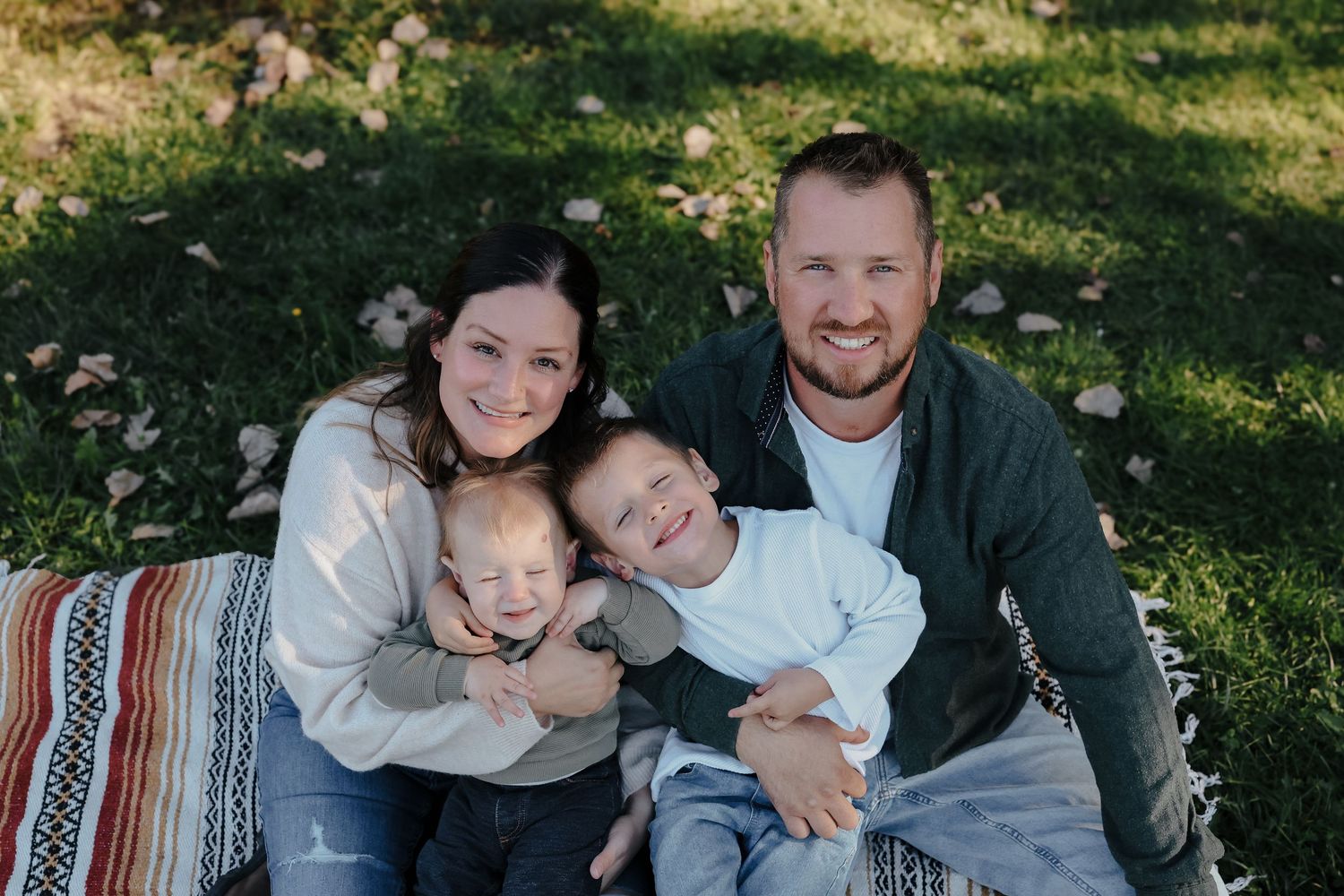 A cheerful family posing together among autumn foliage in an outdoor setting.