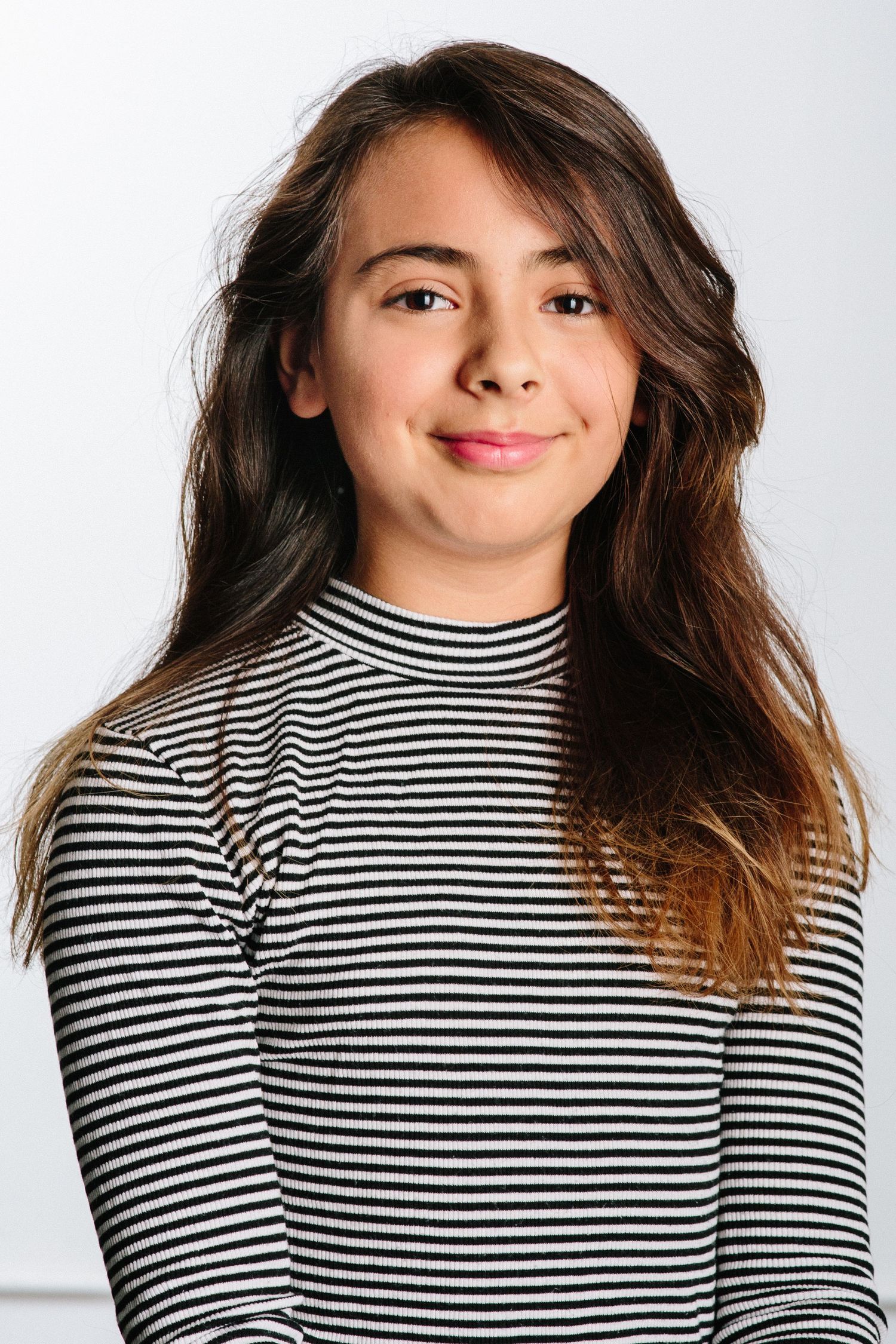 Portrait of young person wearing black and white striped turtleneck against white background.
