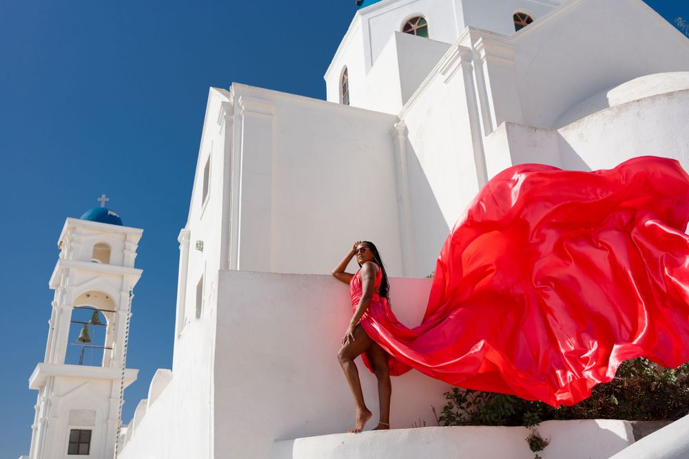 Red flowing fabric creates dramatic movement against classic Greek church architecture.