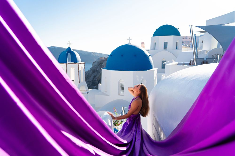 Billowing purple fabric creates dramatic scene against classic Santorini church domes.