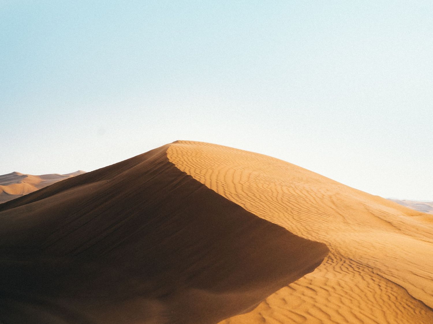 an empty sand dune with clear blue skies