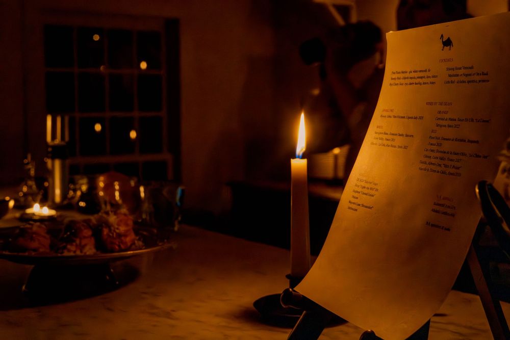 Candlelit table setting with a menu or document in atmospheric lighting.