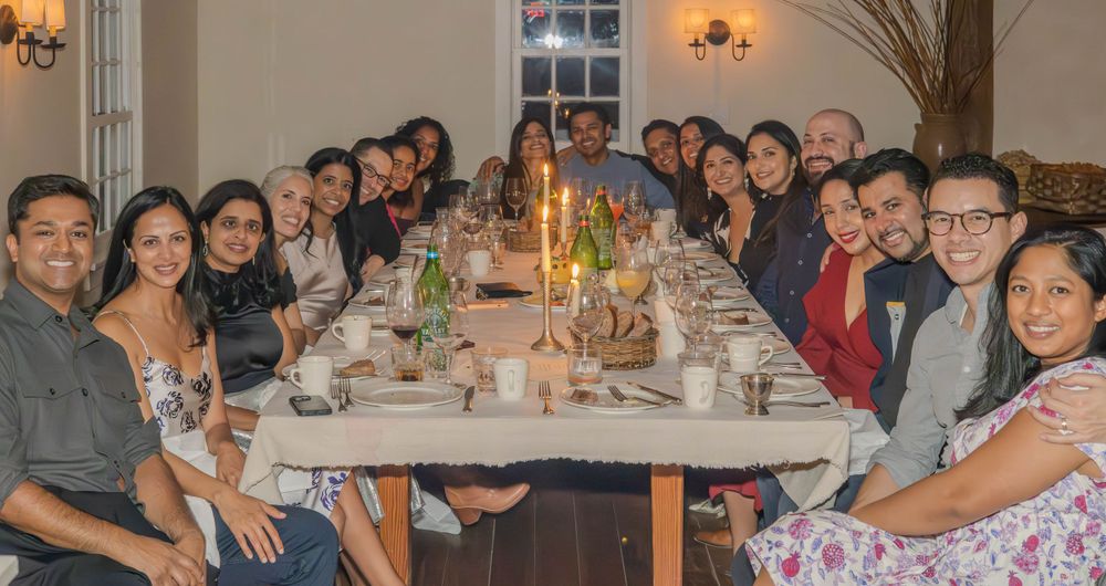 Dinner party guests seated around a long table with candles and decorative centerpieces.