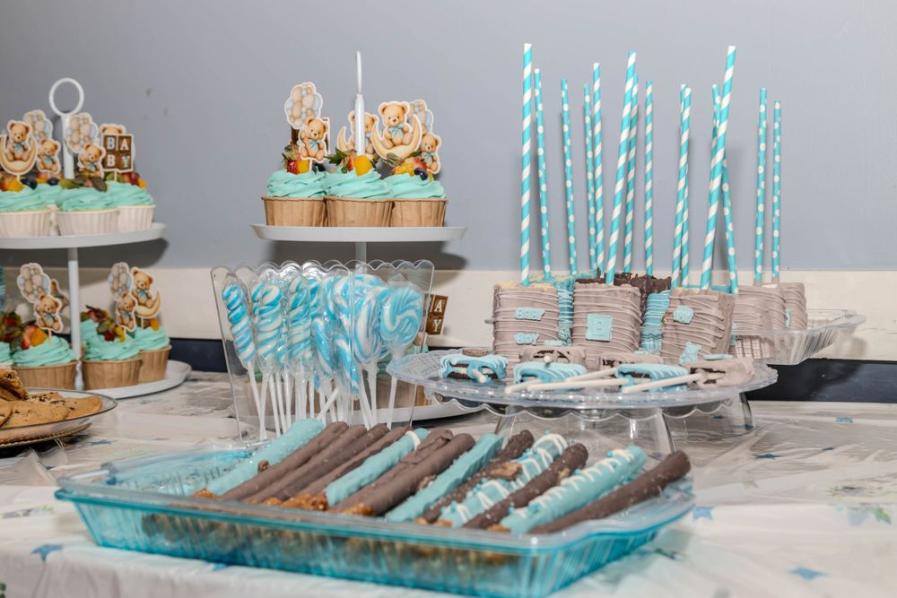 Blue and white themed baby shower dessert table with decorated cookies, cupcakes and striped paper straws.