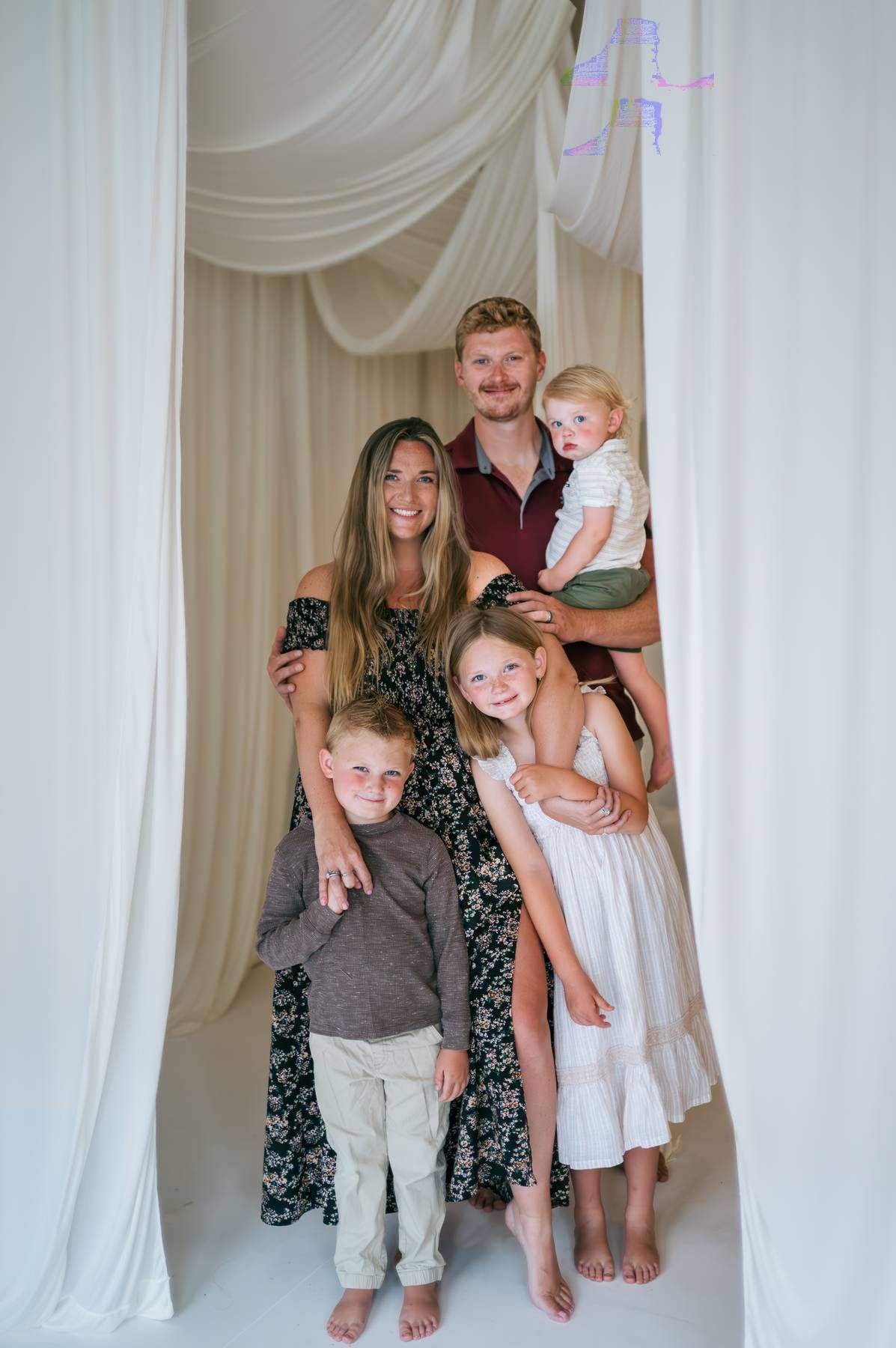 Happy family of five posing together in a bright white draped studio, family photographer North Carolina