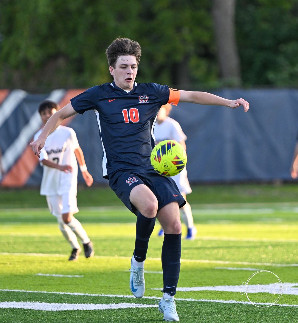 Soccer player in navy uniform prepares to kick bright yellow ball during match.