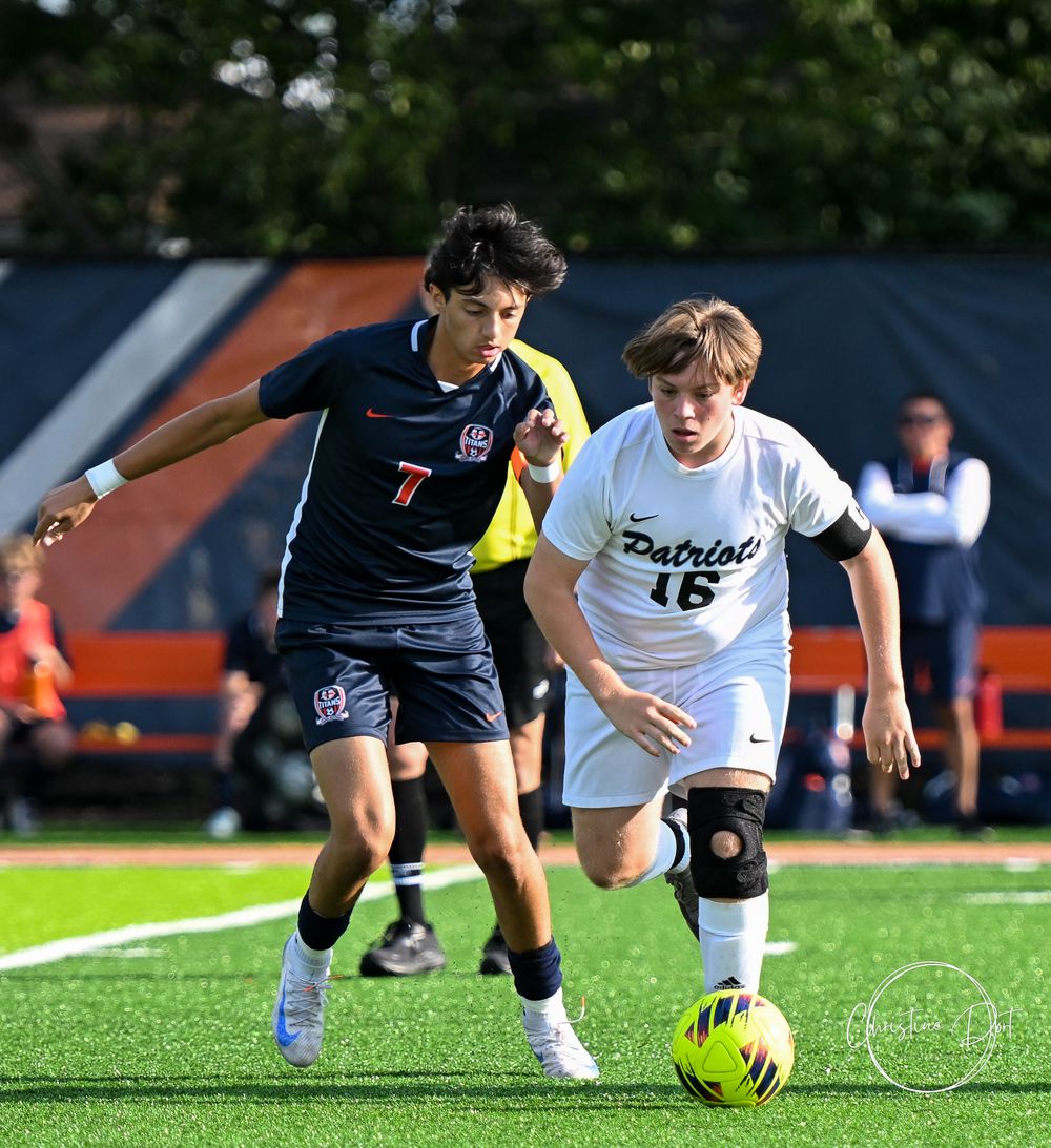 Soccer players compete for control of a bright yellow ball on a grass field.