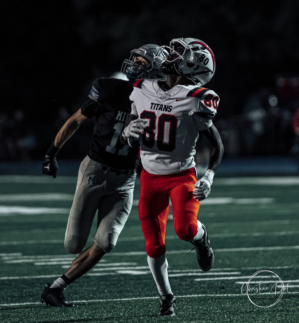 Dynamic high school football action shot showing a tackle between two players during a nighttime game.