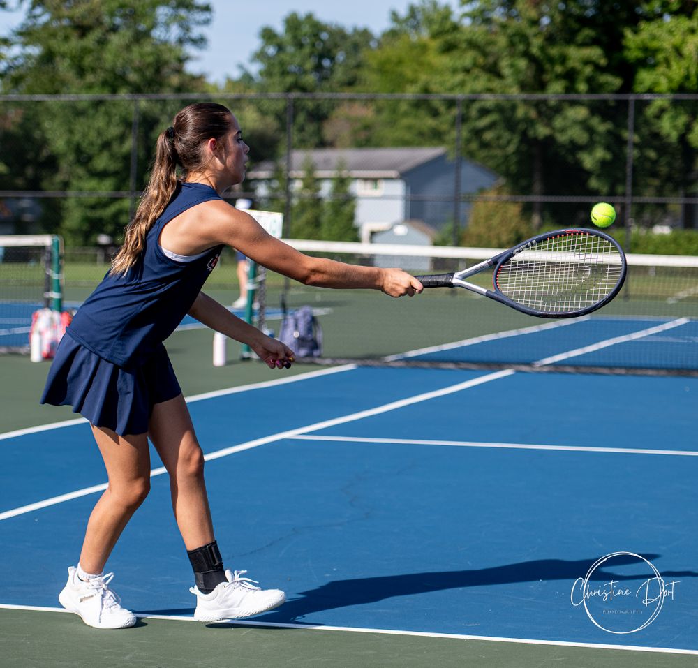 Tennis athlete in navy uniform hitting forehand stroke on blue court.