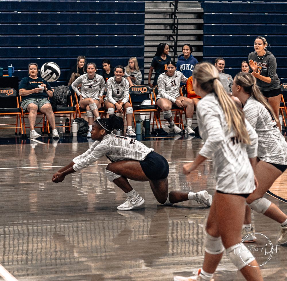Volleyball players diving for the ball during an indoor match.
