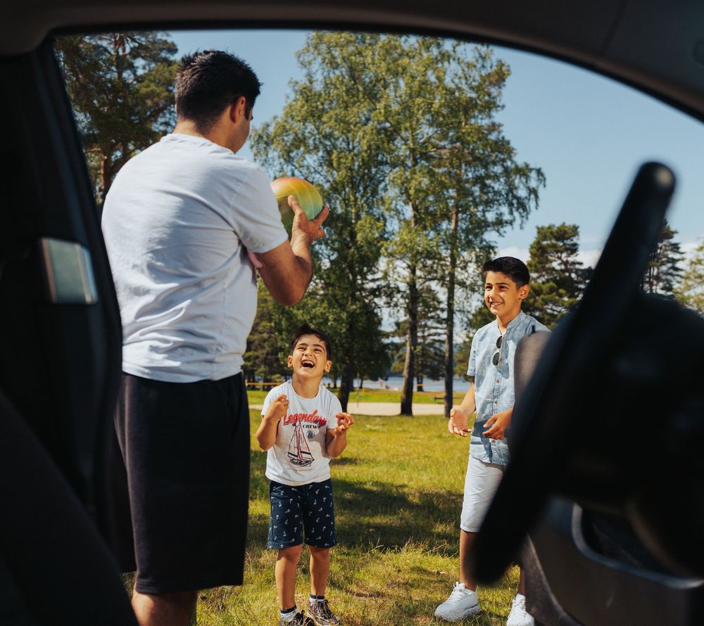 People enjoying a sunny day outdoors viewed through a car window.