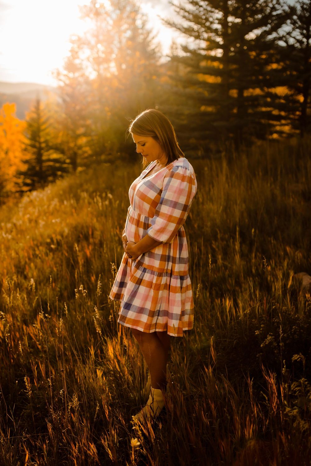 A pregnant mother smiles softly in Vail Colorado mountains