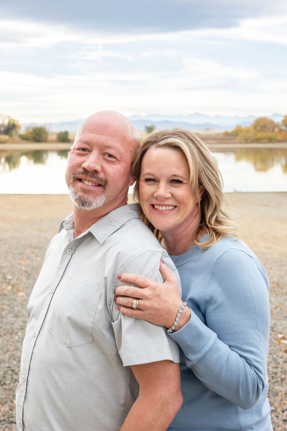Outdoor lakeside portrait of couple wearing casual attire.