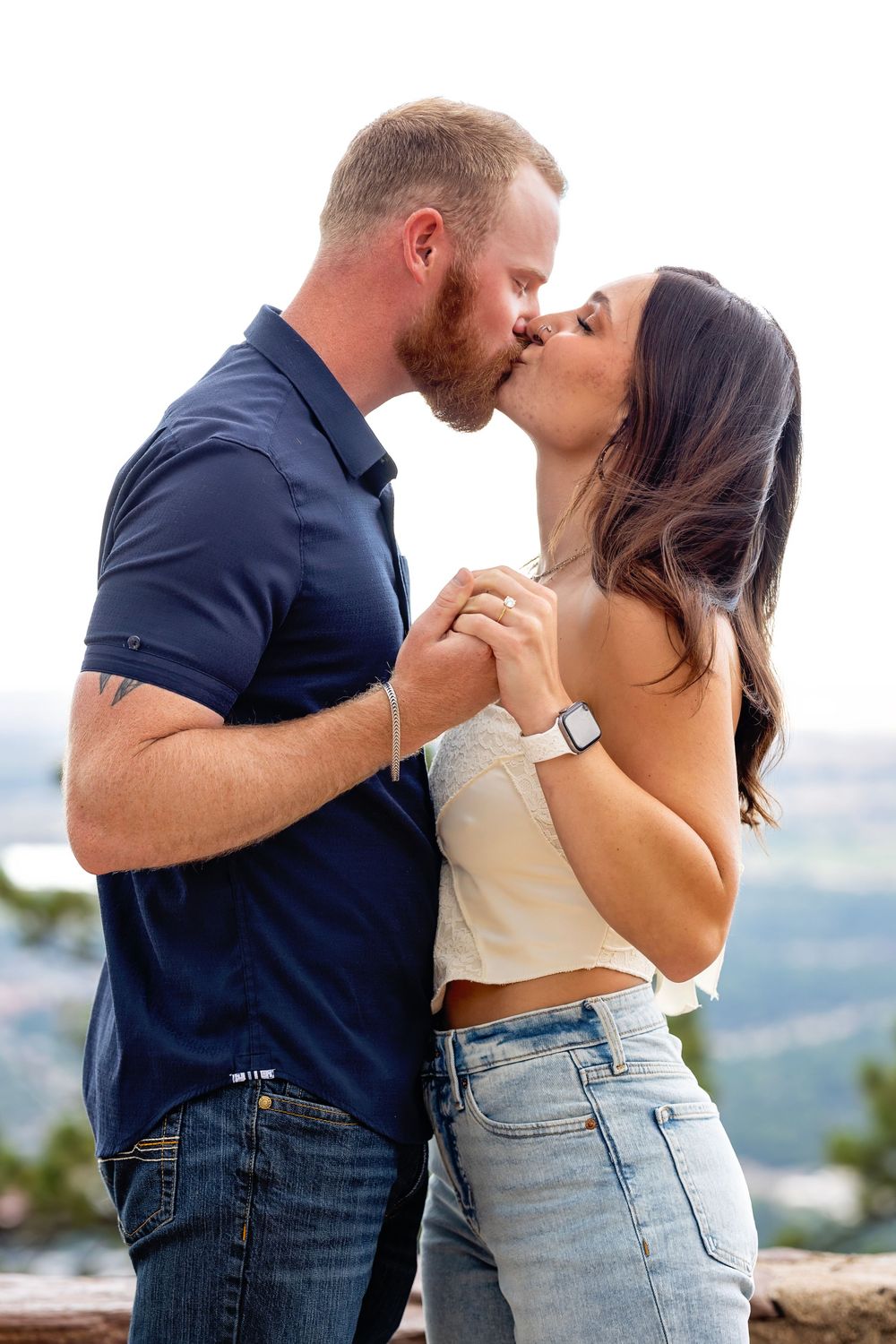 Romantic couple sharing intimate moment with mountain landscape backdrop.