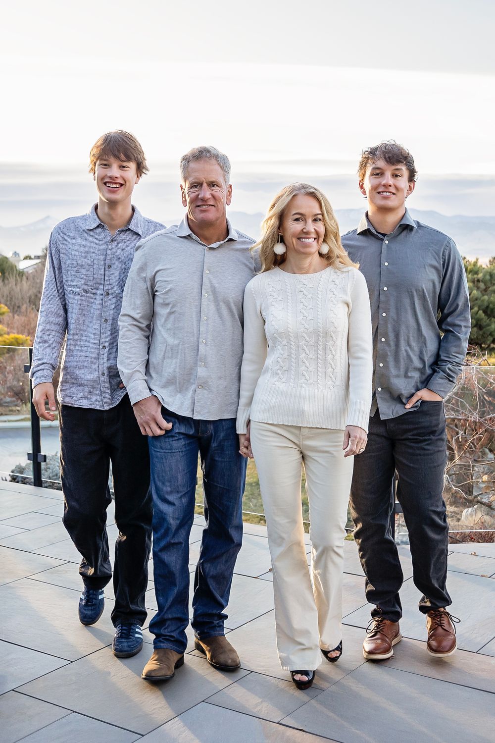 Family portrait of four standing together on outdoor patio with mountain view.