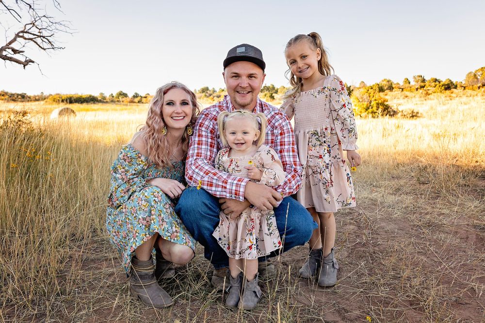 Family portrait in rustic field setting during golden hour.