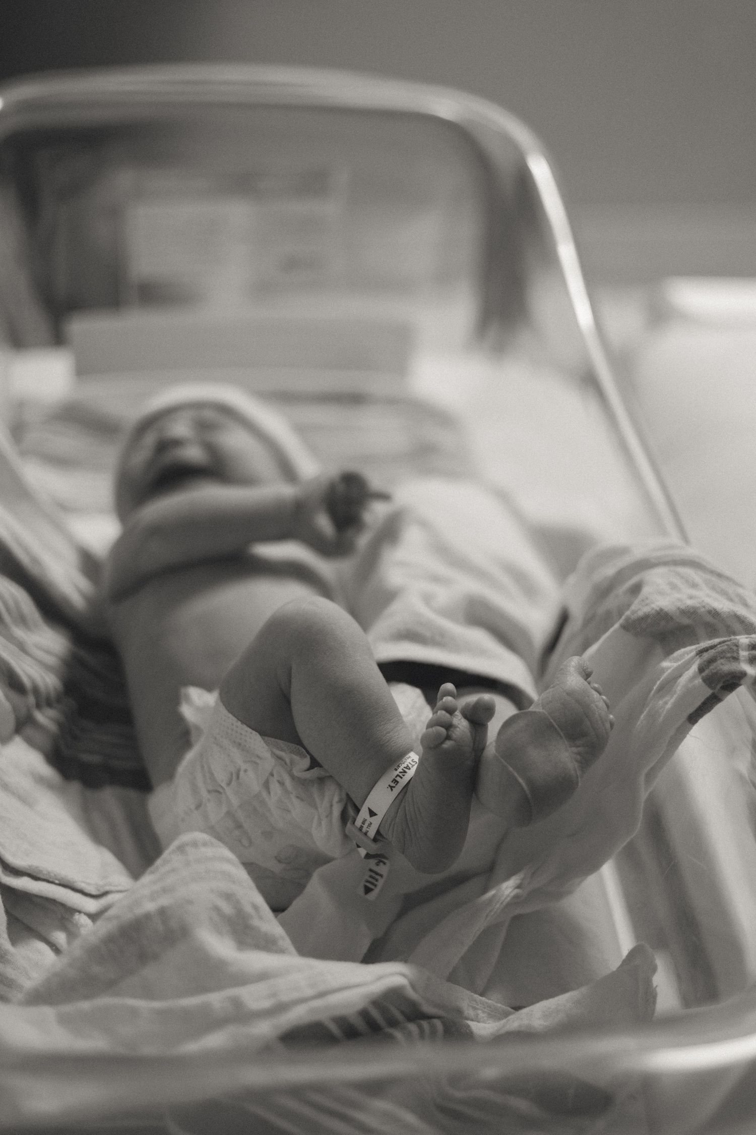 Black and white newborn baby photo in hospital bassinet after birth.