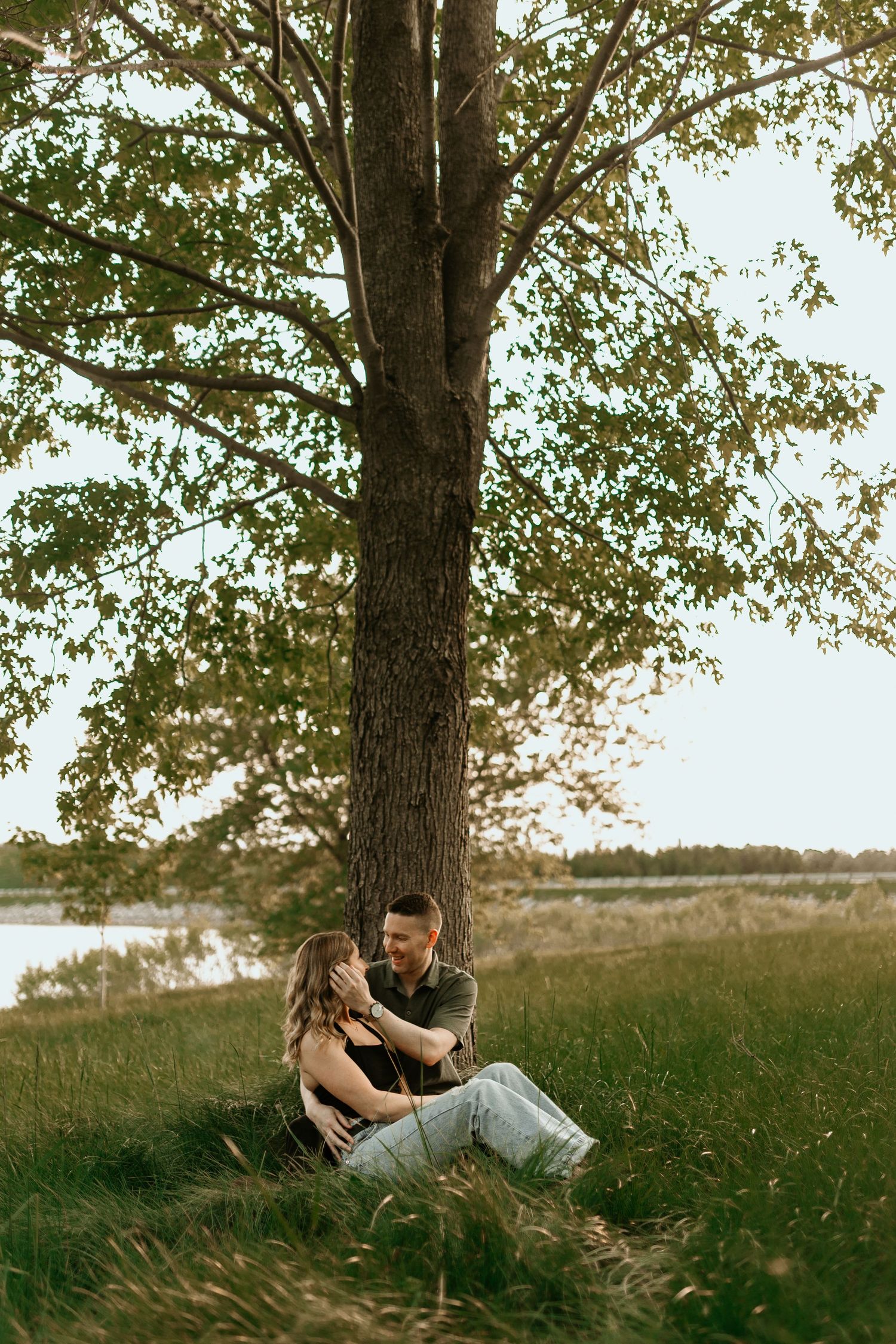 Two hands clasped together tenderly while lying on the ground in white clothing.