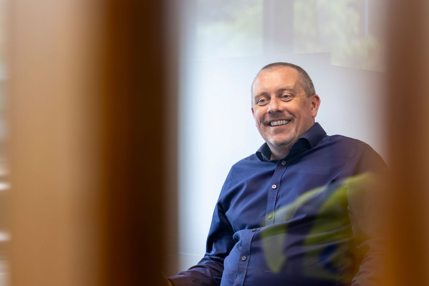 Senior executive in navy sweater smiling warmly during casual business meeting.